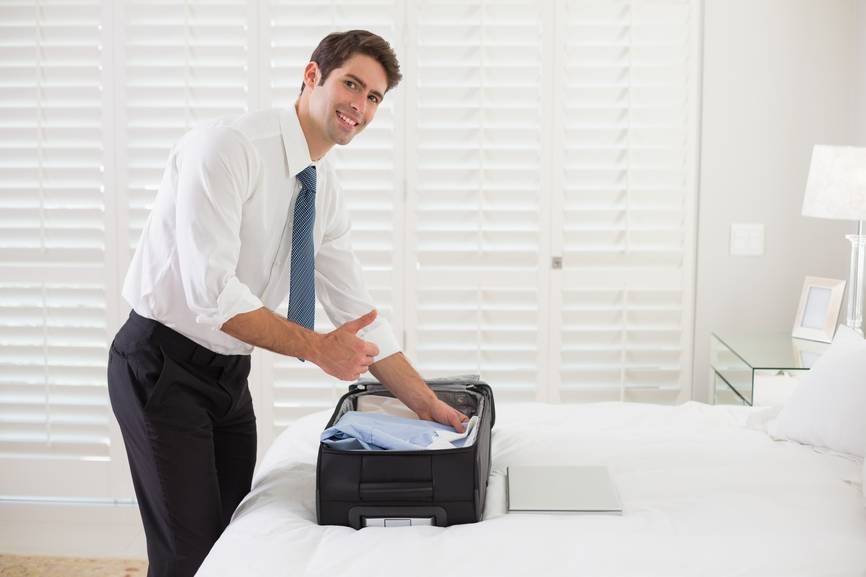 A man puts a folded shirt in a suitcase