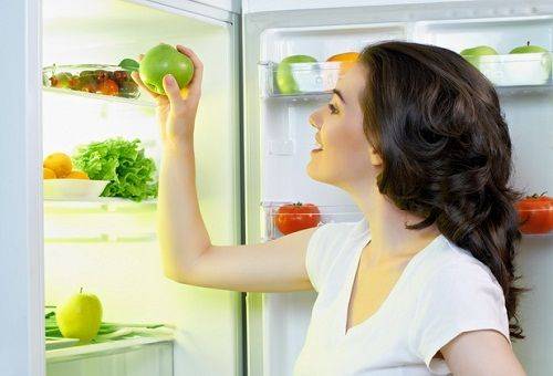 girl with an apple by the fridge