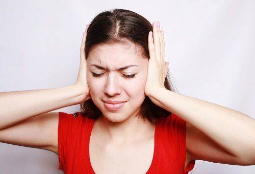 Young woman covers her ears