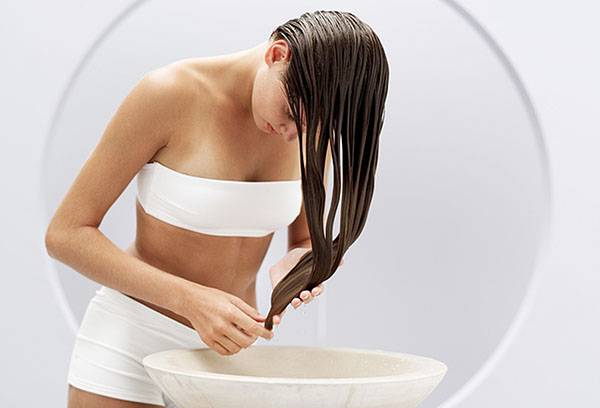 A girl washes her head in a herbal broth