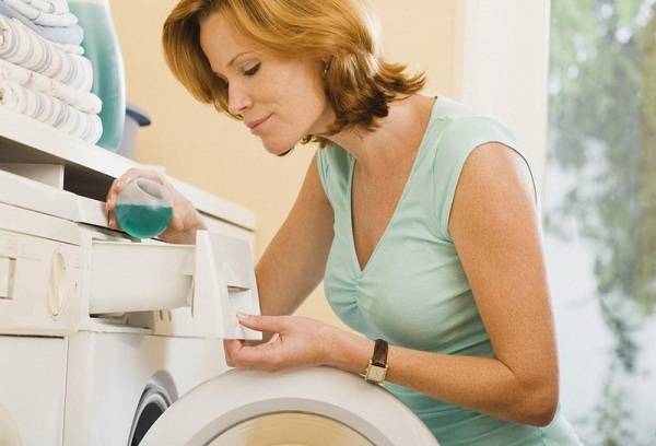 woman pours gel into a washing machine