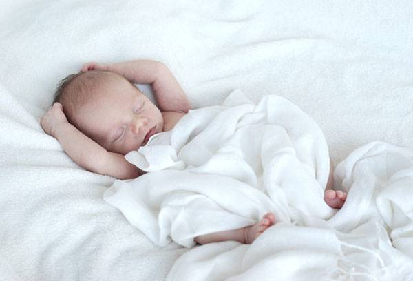 Sleeping baby under a light blanket