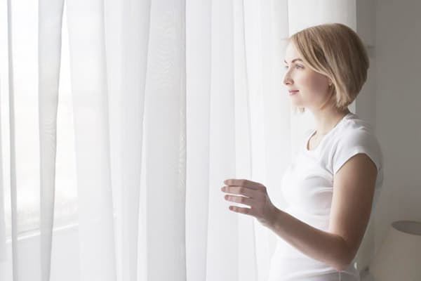 Girl at the window with a white curtain