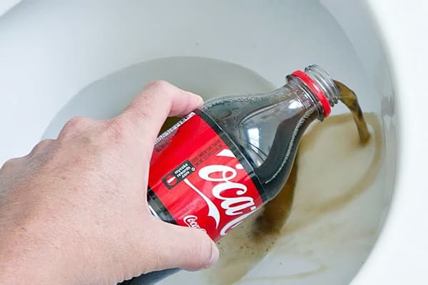 Cilvēks ielej Coca-Cola tualetē
