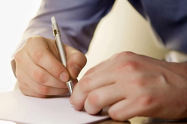 A man writes in a notebook
