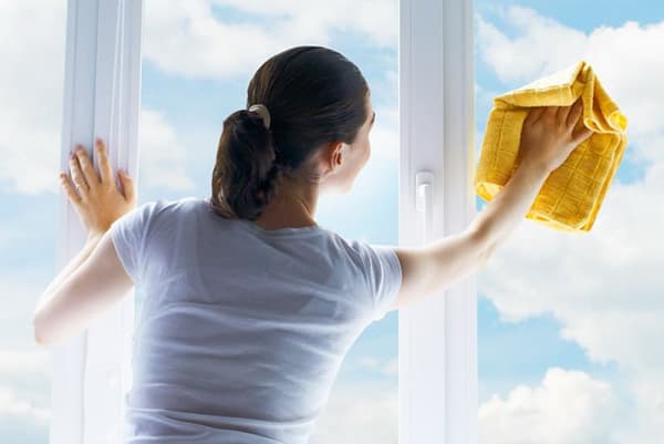 Woman washes a window in sunny weather