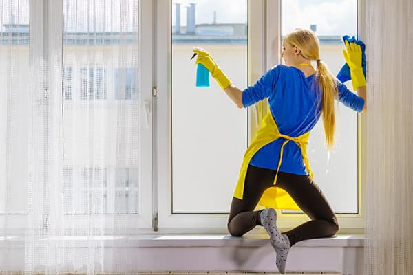 The girl on the windowsill washes a window