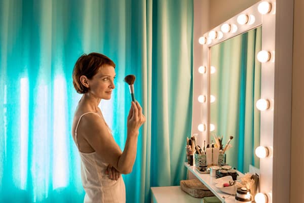 Woman applying makeup in front of a mirror